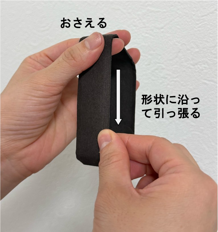 布のシワの伸ばし方その1。片スタの布の端を上下から指の腹でつまみ、上側をおさえながら、形状に沿って下方向へ引っ張っている写真。